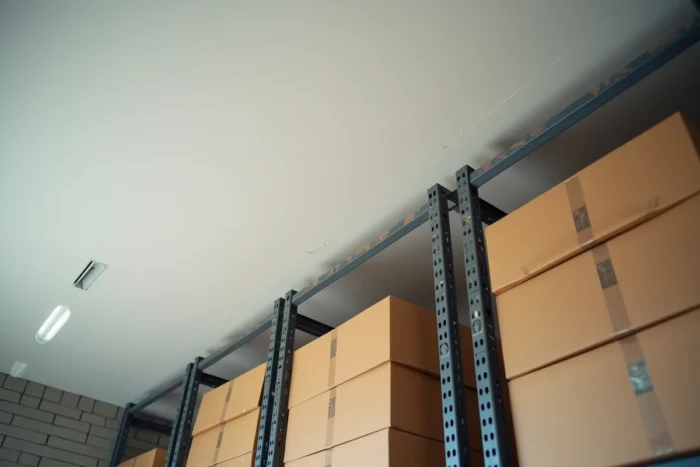 Rack de stockage lourd fixé au plafond en placo d'un garage avec boîtes et caisses à outils empilées